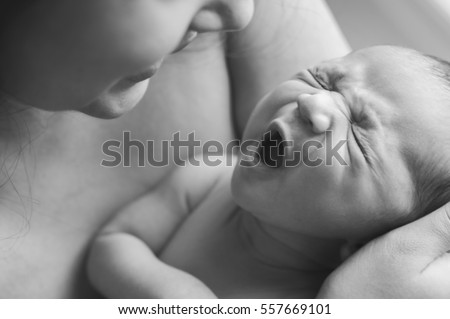 A newborn baby yawning in her mother's arms