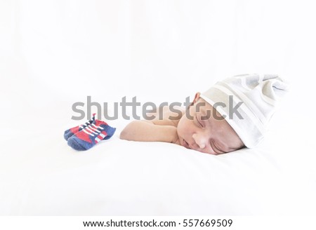 A cute newborn baby boy sleeping on his tummy against a white background