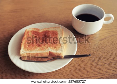 Diet set, plate of one toast with a cup of black coffee on wooden table background, vintage toned color image.