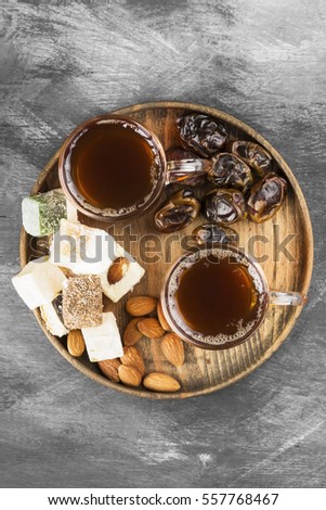 Black tea, oriental sweets, dates and nuts on a dark background. Top view. Food background.