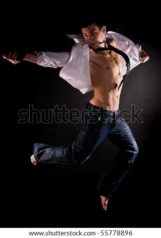 Dramatic light photo of modern acrobat jumping in front of black background
