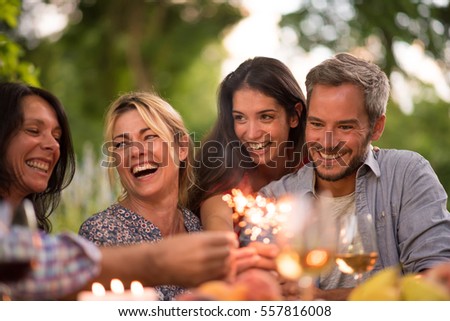 A group of friends having fun on a terrace on a summer evening, they hold spark sticks in their hands