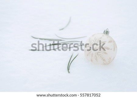 Christmas ball, Christmas tree needles, golden serpentine lie on the snow.