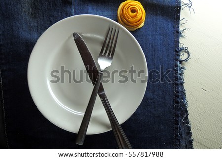 White empty plate and fork and knife on wooden texture background