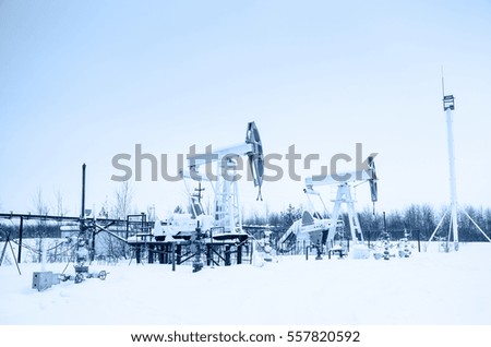 Group of oil pumps and wellheads in the oilfield during winter. Oil and gas concept. Toned.