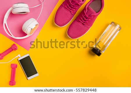 Athlete's set with female clothing, dumbbells and bottle of water on yellow background Royalty-Free Stock Photo #557829448