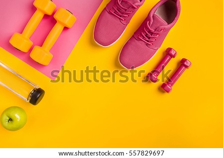 Athlete's set with female clothing, dumbbells and bottle of water on yellow background Royalty-Free Stock Photo #557829697