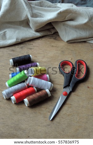 Colored thread and scissors on wooden background. Background