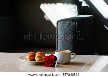 Cup of coffee, croissants and rose on table in room, romantic breakfast, Valentine Concept