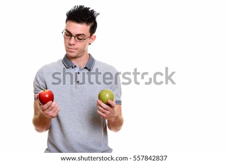 Studio shot of young man choosing between red apple and green apple isolated against white background