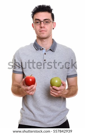 Studio shot of young man holding red apple and green apple isolated against white background