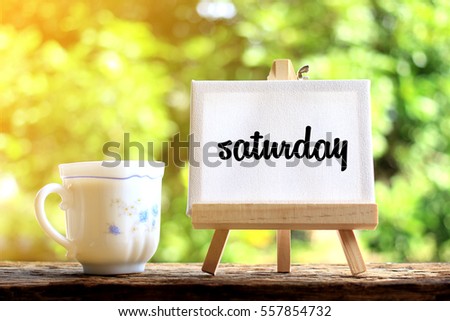 Saturday. concept of coffee cup with stand board on morning background