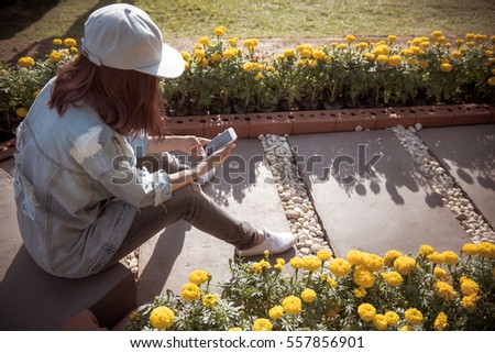 young woman using smart phone in the garden,Vintage style photo.