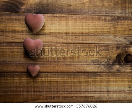 three purple hearts on a dark wooden background, concept of Valentine's day, space