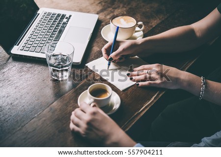 Two women discussing business projects in a cafe while having coffee. Startup, ideas and brain storm concept. Toned picture
