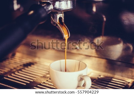 Coffee made in professional espresso machine pouring into a cup. Toned picture