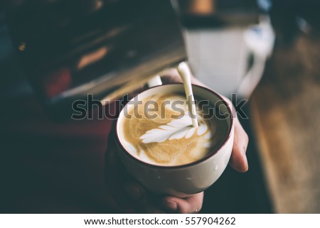 Barista pours milk making cappuccino or latte. Toned picture