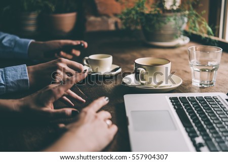 Two women discussing business projects in a cafe while having coffee. Toned picture