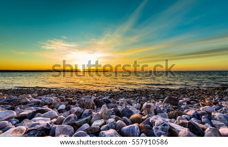 Stones on a beach with sunset on the ocean sea. Landscape photo of sunrise or sunset on a natural beach in Piran, Slovenia.