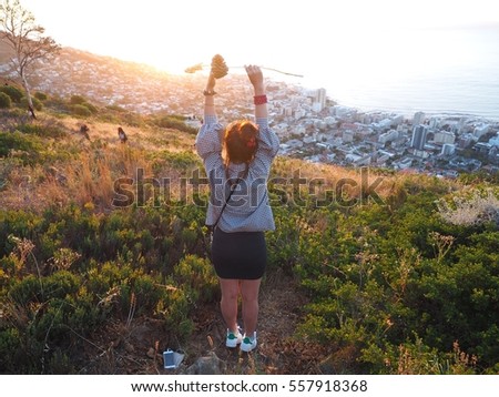 Young girl hands up and standing with during sunset on Signal Hill looking to town and sea background in twilight sky of Cape Town, South Africa, Table Mountain national park