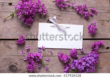 Fresh violet lilac flowers, decorative red heart and empty tag on aged  wooden planks. Selective focus. Place for text.