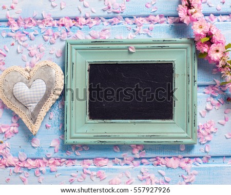 Sakura pink flowers,  decorative heart and empty blackboard  on blue wooden planks. Selective focus. Place for text. Flat lay. Top view. Toned image.