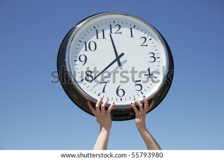 Hands lifting big clock outdoors