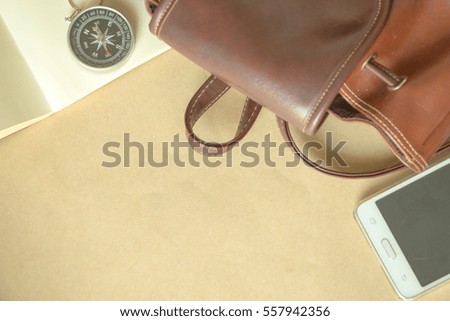 Brown bag with Compass,mobile phone note book and pen copy spaces top view.