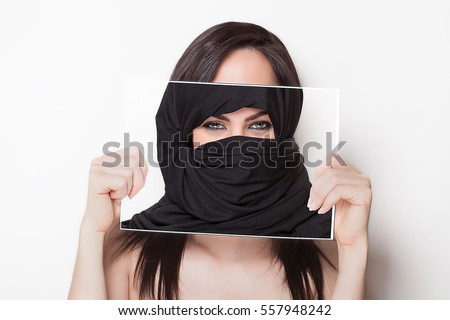 Beautiful girl holding a photo of herself wearing a burqa