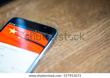 Smartphone on wooden background with 5G network sign 25 per cent charge and China flag on the screen.