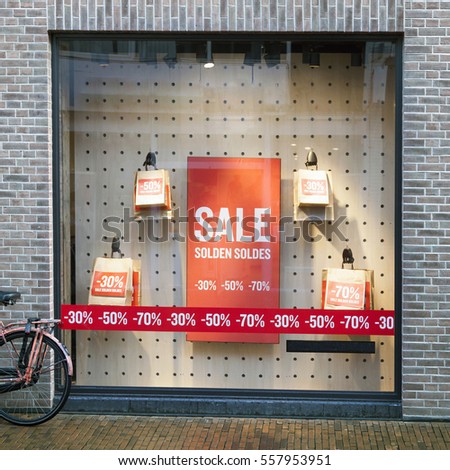 sale signs in display window of clothing store and part of bicycle on the street