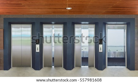 Open and closed chrome metal office building elevator doors realistic photo. Lift transportation floor to floors with push switch for up and down. Royalty-Free Stock Photo #557981608