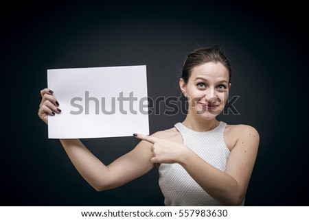 Young woman holding a white blank paper, studio shot on black background