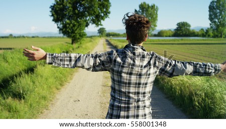 A young boy running in a field with a lot of joy and positive energy in a beautiful sunny day in slow motion