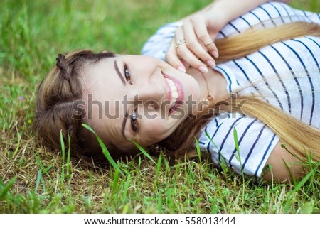 Happy young woman lying on green grass. Warm spring. Summer.