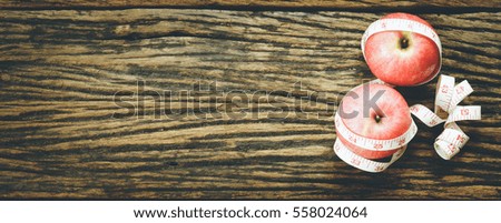 Diet healthy concept. Red apple with measuring tape on wooden background, top view, copy space for text.