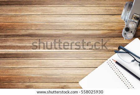 Office desk with blank notebook and black pencil on brown wood background. Top view with copy space for design