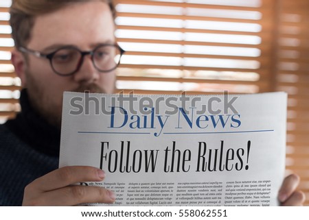 Man reading follow the rules! headlined newspaper