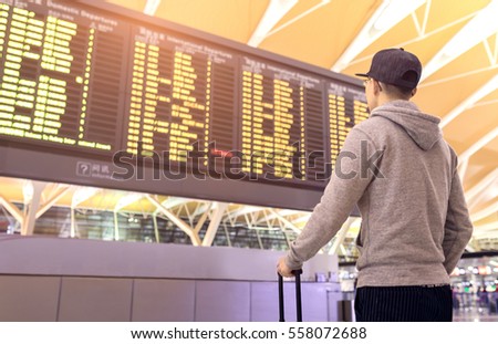 Passenger looking at departures board in airport terminal Royalty-Free Stock Photo #558072688