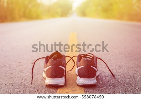 Close up new black running shoes on asphalt road in morning time Royalty-Free Stock Photo #558076450