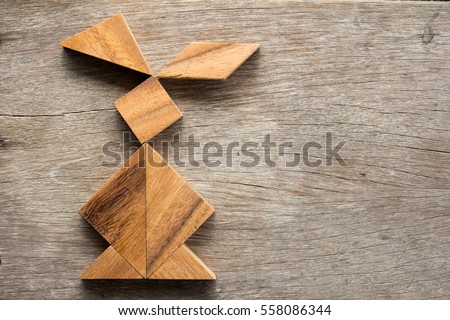 Chinese tangram puzzle in rabbit shape on wooden background (Concept for easter)