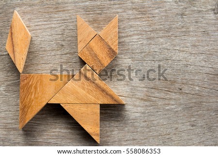 Chinese tangram puzzle in cat shape on wooden background