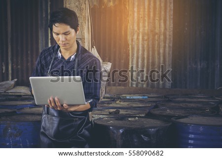 Man Using Laptop Computer on Background of storage room.
