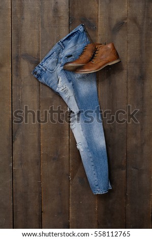Mans boots shoes and blue jeans on wood background