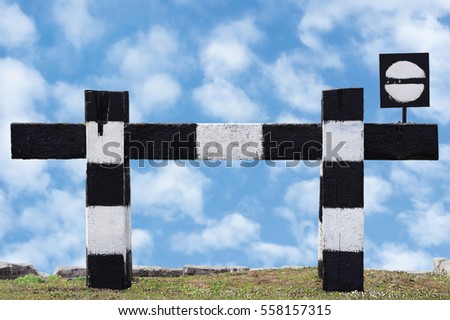 Dead end no through train railroad traffic sign isolated old grungy railway stop signal signage black white striped retro barrier closeup blue bright cloudscape summer sky clouds green grass