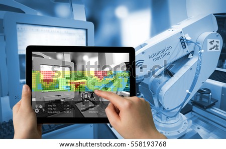 Industry 4.0 concept .Man hand holding tablet with Augmented reality screen software and blue tone of automate wireless Robot arm in smart factory background