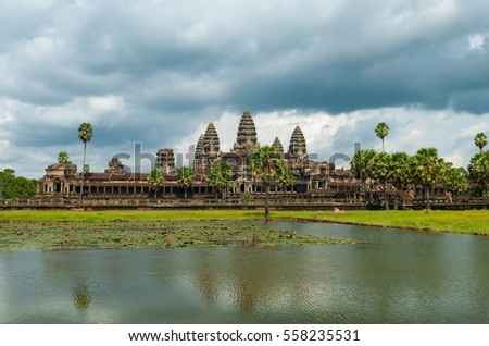 Reflection of the Angkor Wat temple in a man made lagoon with sugar palms during storm weather in the region of Siem Reap, Cambodia.