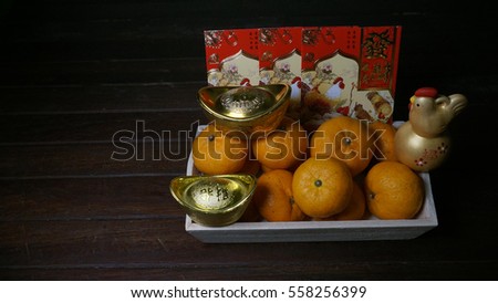Chinese gold ingots, tangerine's and money envelope on a rustic wooden background. Chinese text means lucky, wealth and prosperity. Chinese New Year concept.