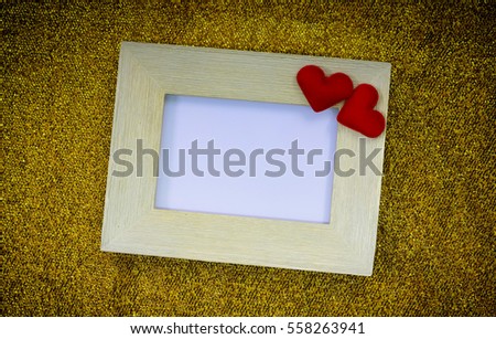 Old wooden frame with red hearts on the gold fabric background.Valentines day concept.