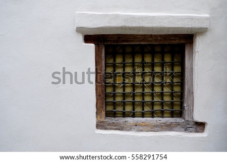 Wooden old dirty window in aged wall with lattice.